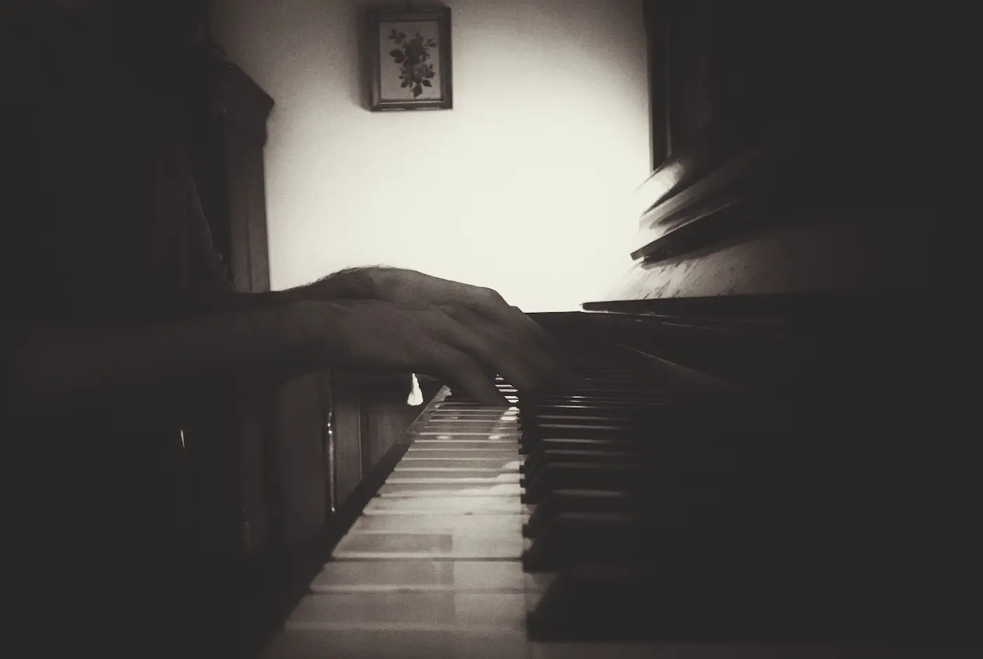 Hands playing a piano in a dark room